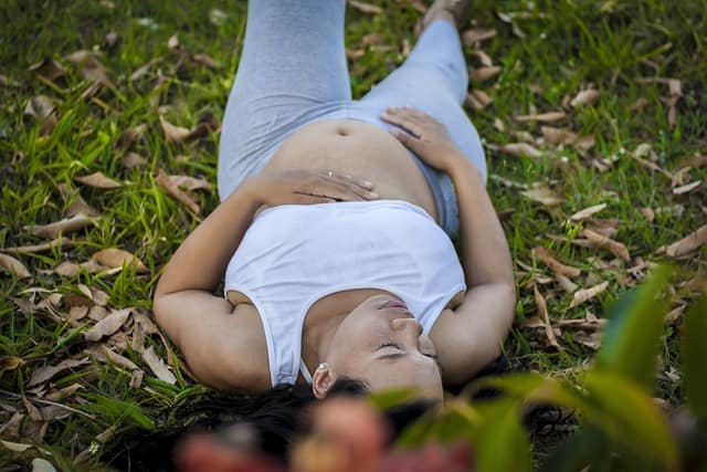 A pregnant woman lying on grass